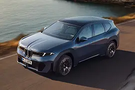2025 BMW iX3 50 xDrive front three-quarter view by the sea – luxury electric SUV