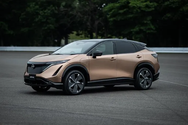 Front view of the Nissan Ariya, showcasing its distinctive V-motion grille, slim LED headlights, and aerodynamic design, highlighting its modern electric vehicle aesthetics.